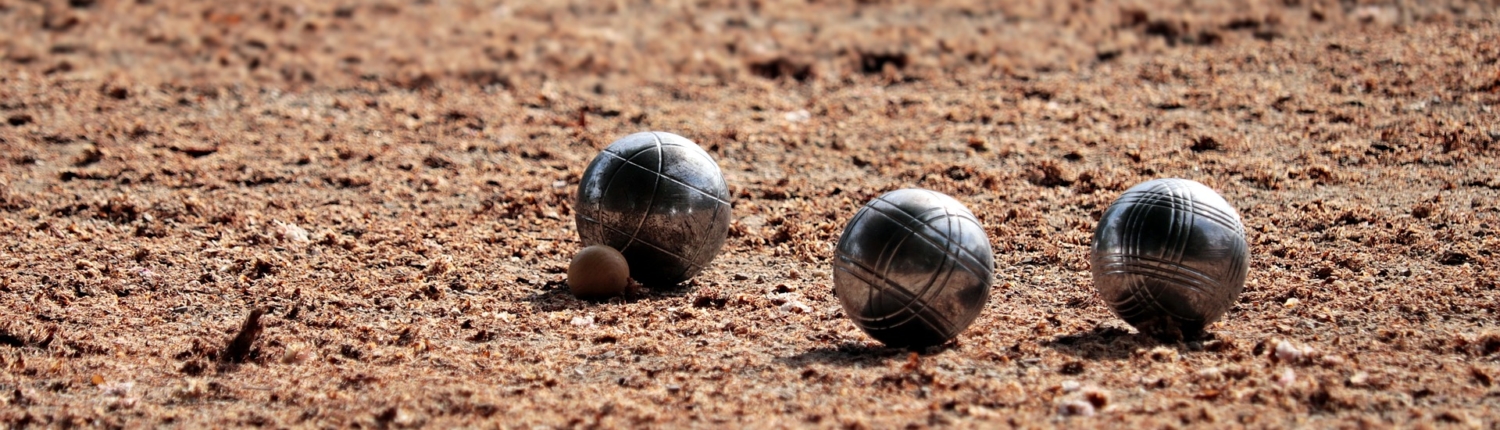 Trois boules de pétanque et un cochonnet sur un terrain de terre