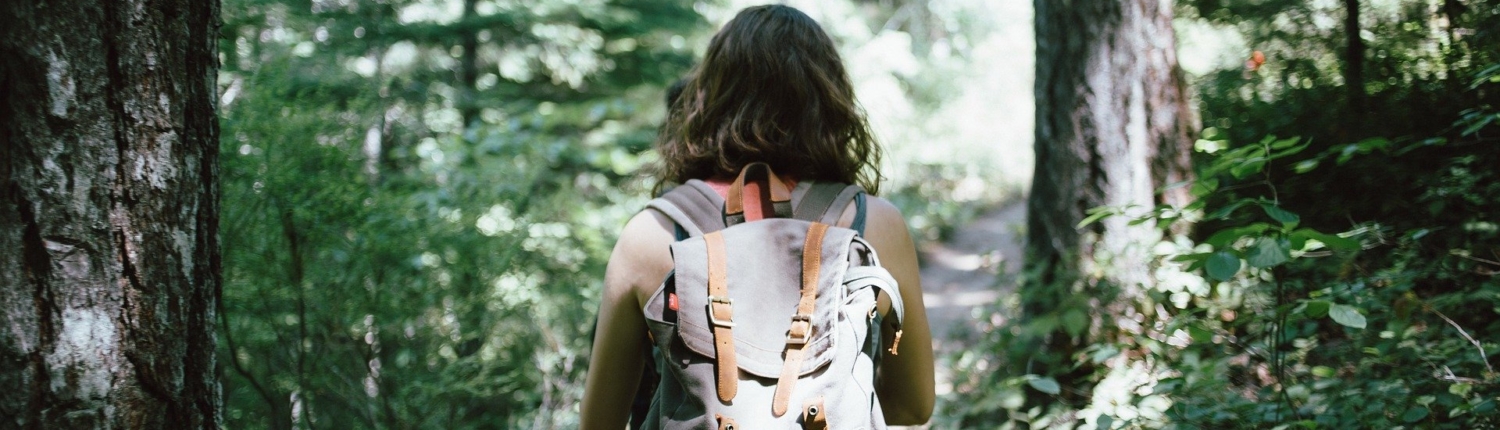 Femme en sac à dos en train de faire une randonnée pédestre dans les bois